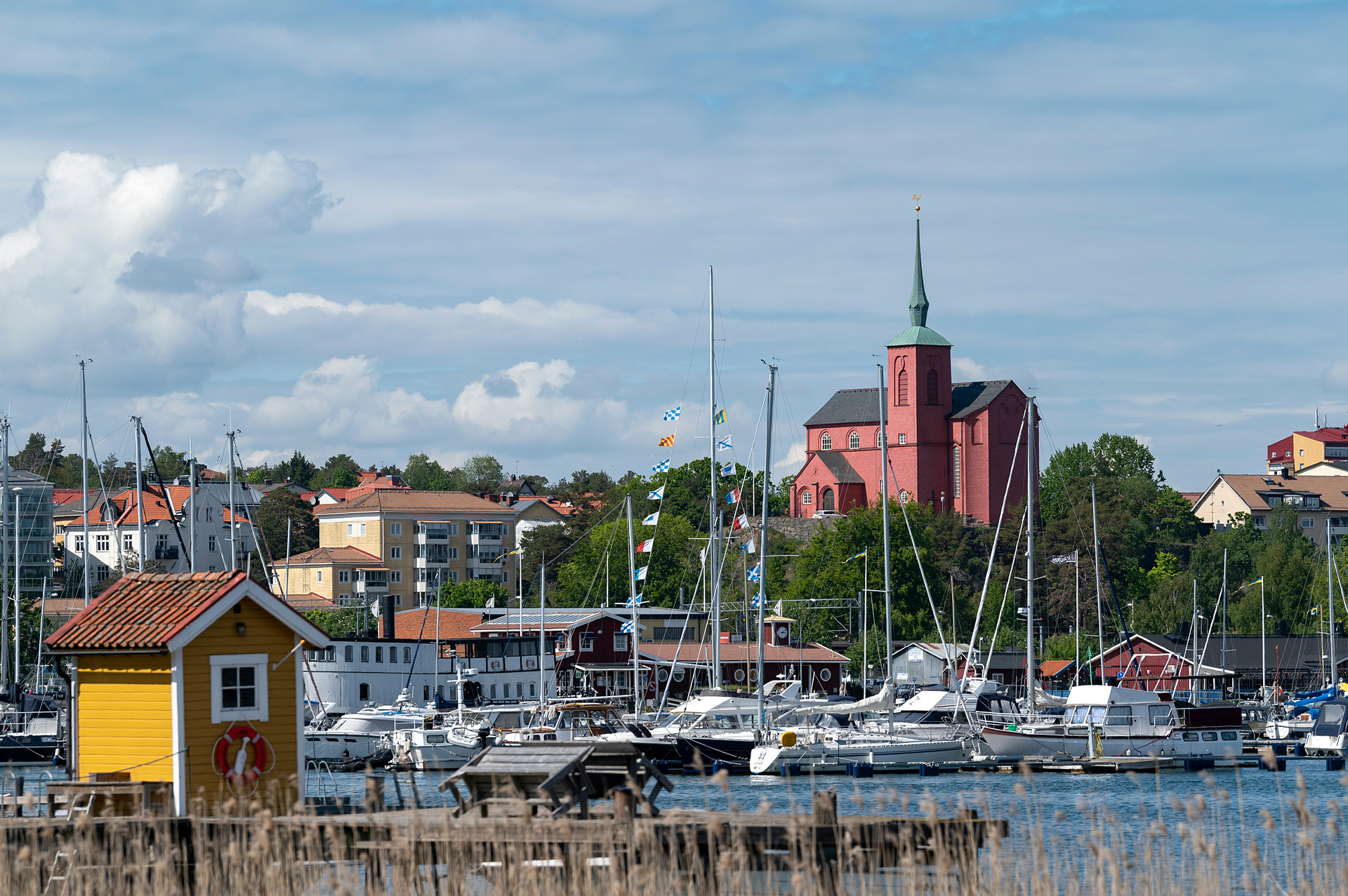 Nynäshamns kyrka på en höjd med gästhamnen i förgrunden.